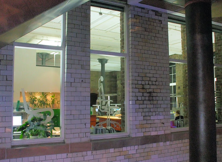 View of office space at Lighthouse from atrium showing structural cast-iron columns within original building