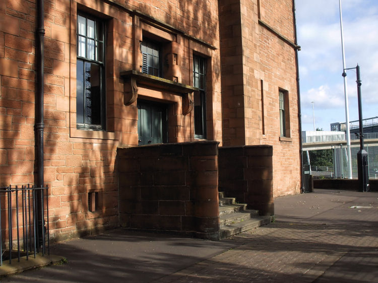 Dappled sunshine at rear entrance of Martyrs School, looking towards footbridge over M8 motorway