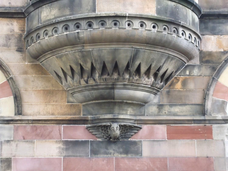Carved owl in banded stonework at Chroma Building