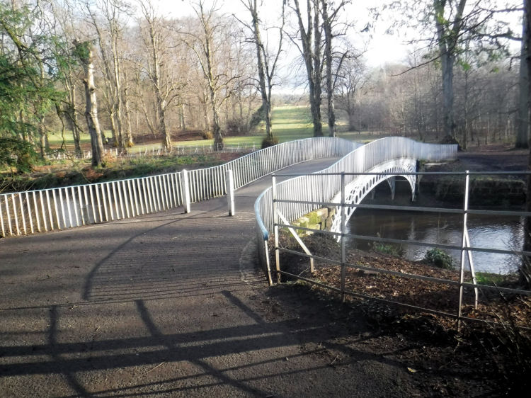 White iron bridge, cast as a single span, leads to the Netherlee section of the park