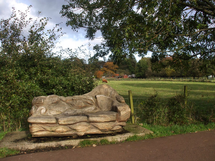 Park bench on riverside path, carved from old tree trunk
