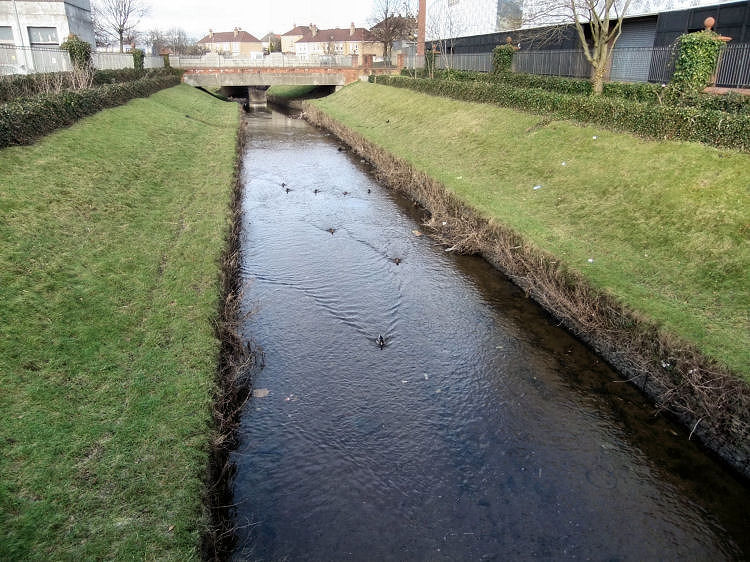Canalised section of Brock Burn flowing past Silverburn Shopping Centre towards bridge at Barrhead Road