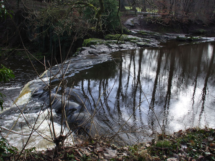 Reflections on river flowing towards waterfall